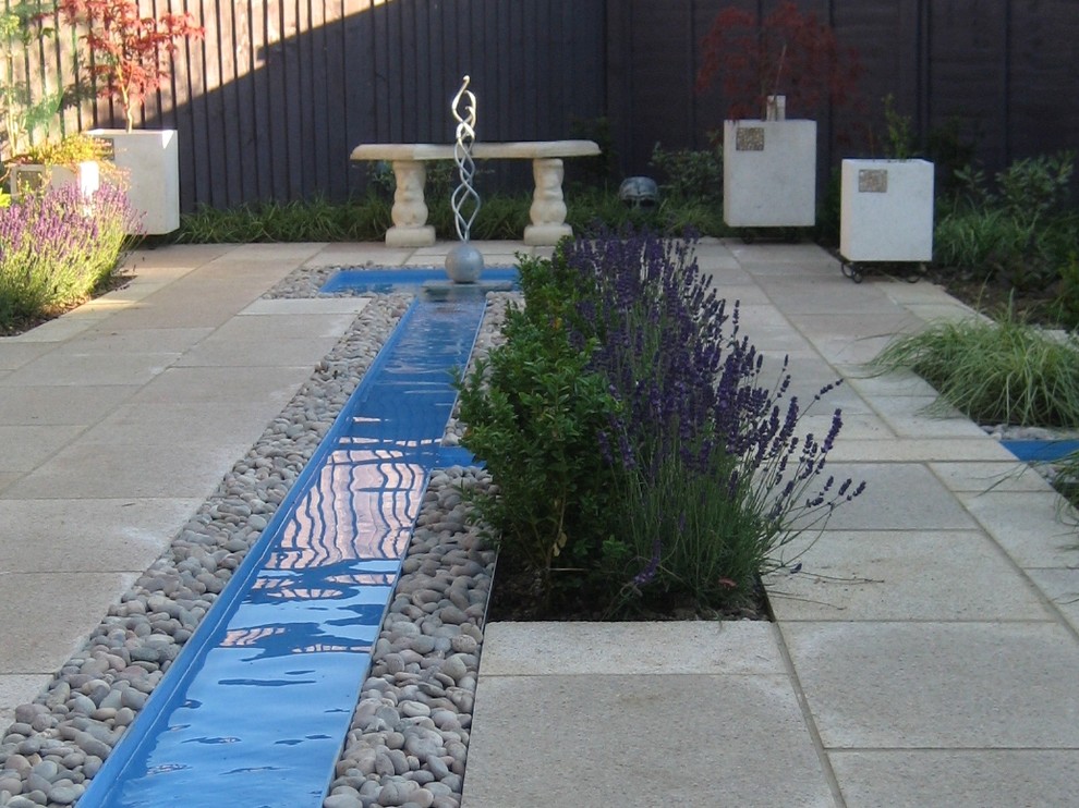 Ispirazione per un giardino formale minimalista esposto a mezz'ombra in cortile e di medie dimensioni con pavimentazioni in pietra naturale e fontane