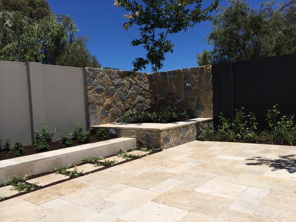 Cette image montre un petit jardin méditerranéen l'été avec une exposition partiellement ombragée et des pavés en pierre naturelle.