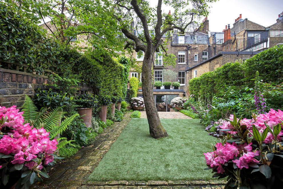 На фото: регулярный сад на заднем дворе в классическом стиле с мощением клинкерной брусчаткой с