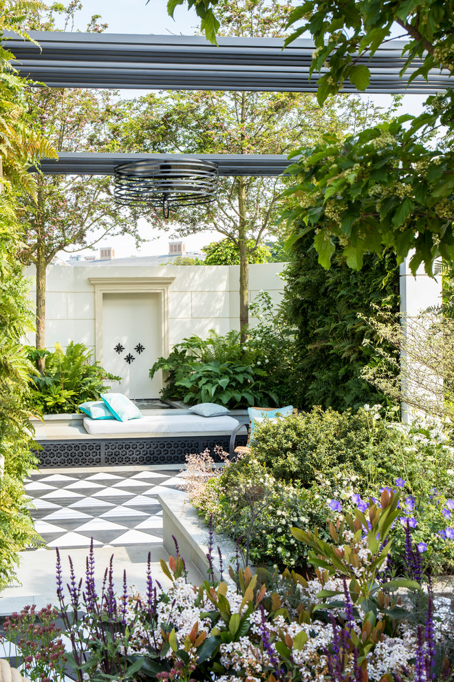 Inspiration for a mediterranean stone landscaping in London with a pergola.