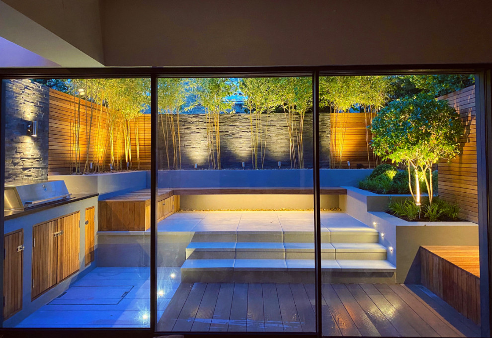 This is an example of a small contemporary back garden in London with a wood fence.