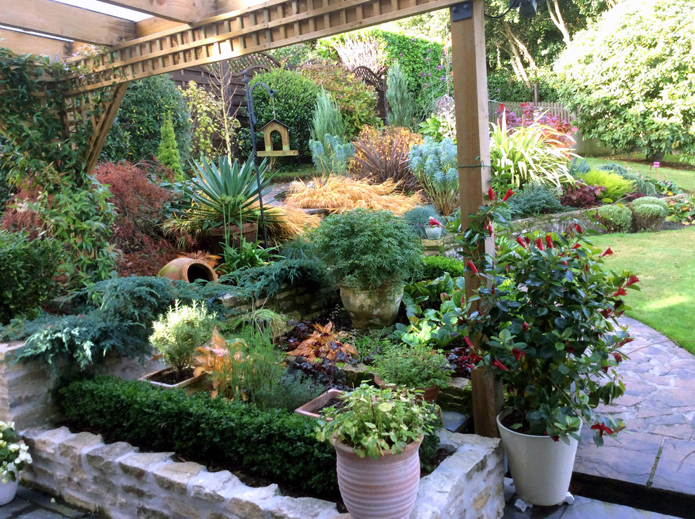Foto di un grande giardino formale classico in ombra dietro casa in autunno con un giardino in vaso, gazebo e pavimentazioni in pietra naturale