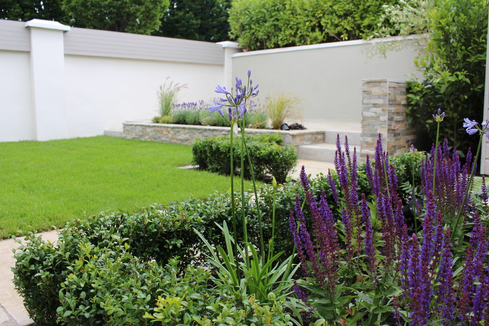 Cette photo montre un grand jardin arrière chic avec une exposition partiellement ombragée et des pavés en pierre naturelle.