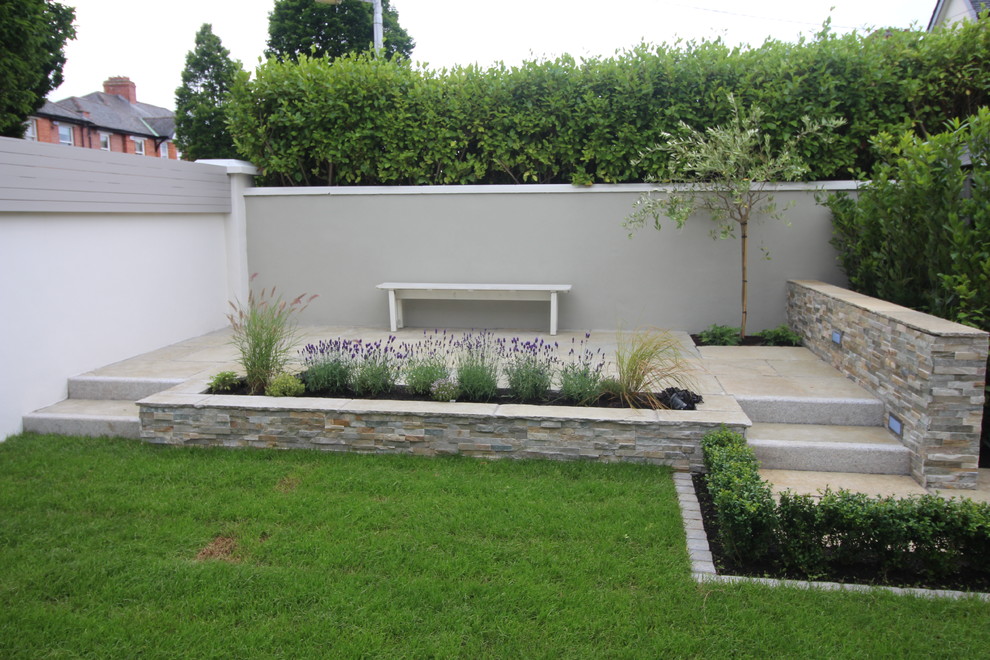 Réalisation d'un jardin arrière tradition avec une exposition partiellement ombragée et des pavés en pierre naturelle.