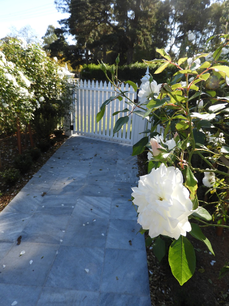 Foto de camino de jardín de estilo de casa de campo grande en verano en patio delantero con jardín francés, exposición total al sol y adoquines de piedra natural