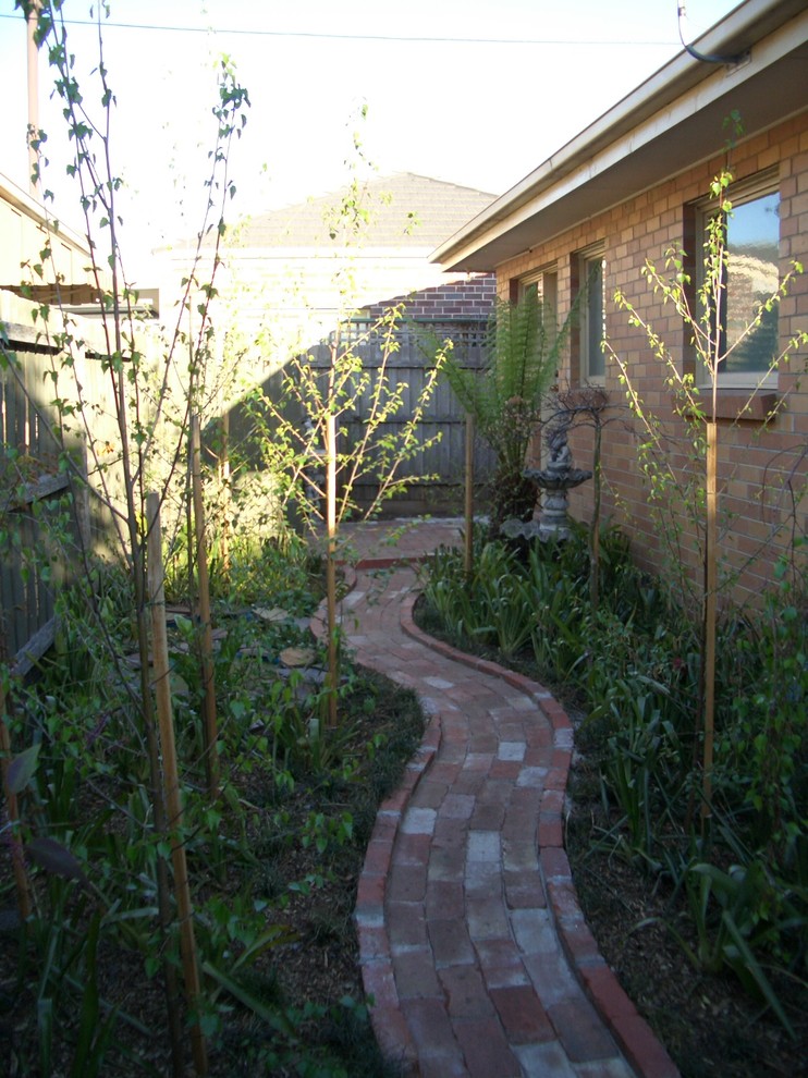 Cette photo montre un petit aménagement d'entrée ou allée de jardin latéral tendance avec une exposition partiellement ombragée et des pavés en brique.