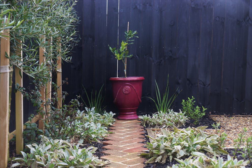 This is an example of a medium sized country front partial sun garden for summer in Auckland with brick paving.