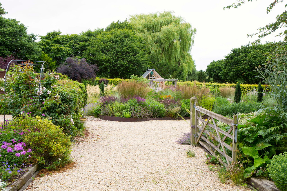 オックスフォードシャーにある広い、夏のおしゃれな裏庭 (庭への小道、砂利舗装) の写真
