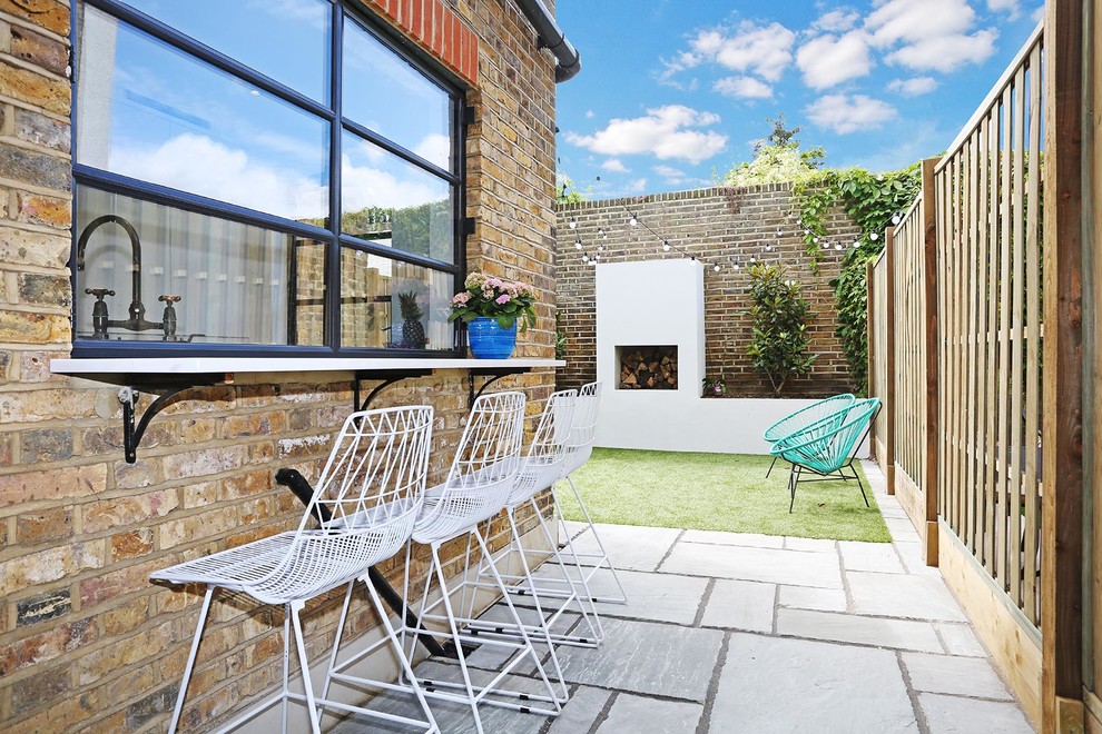 This is an example of a mid-sized contemporary backyard concrete paver landscaping in London with a fire pit.