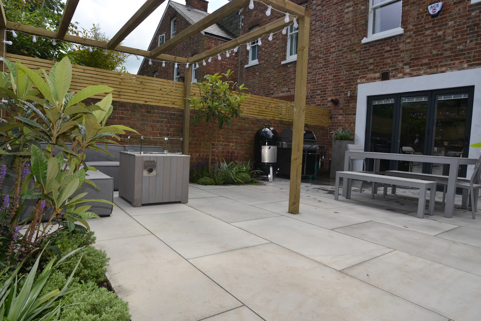 This is an example of a small contemporary back patio in Sussex with a fire feature and natural stone paving.