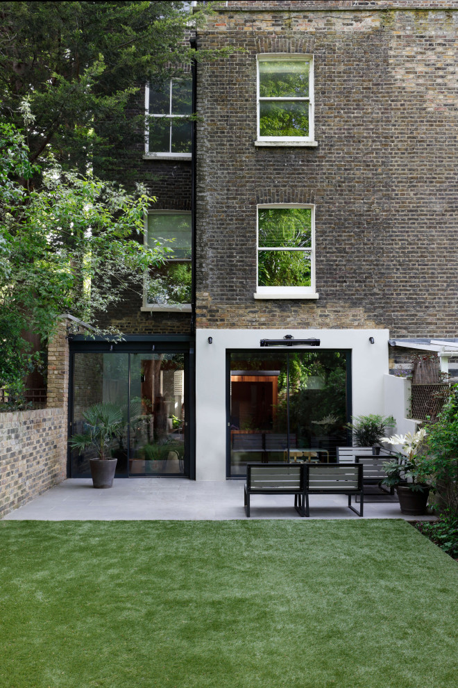Geometrischer, Großer Moderner Garten im Sommer, hinter dem Haus mit Sichtschutz, direkter Sonneneinstrahlung und Betonboden in London