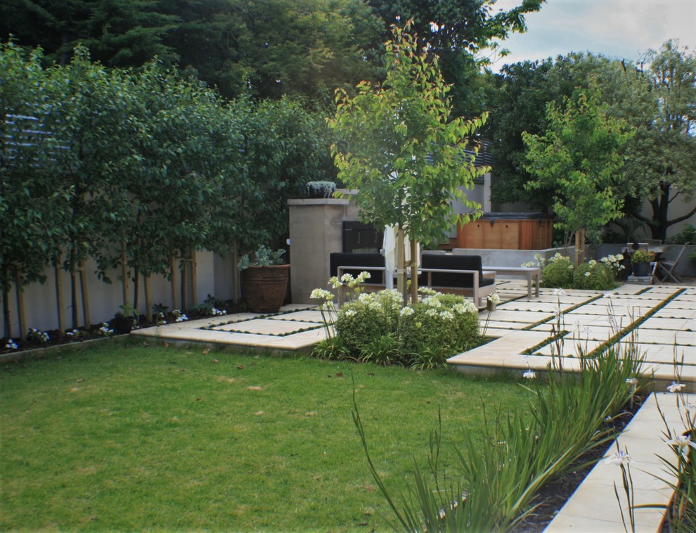 Cette photo montre un jardin arrière chic de taille moyenne avec une exposition partiellement ombragée et des pavés en béton.
