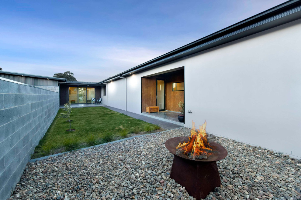 This is an example of a mid-sized contemporary partial sun hillside river rock formal garden in Canberra - Queanbeyan with a fire pit for winter.