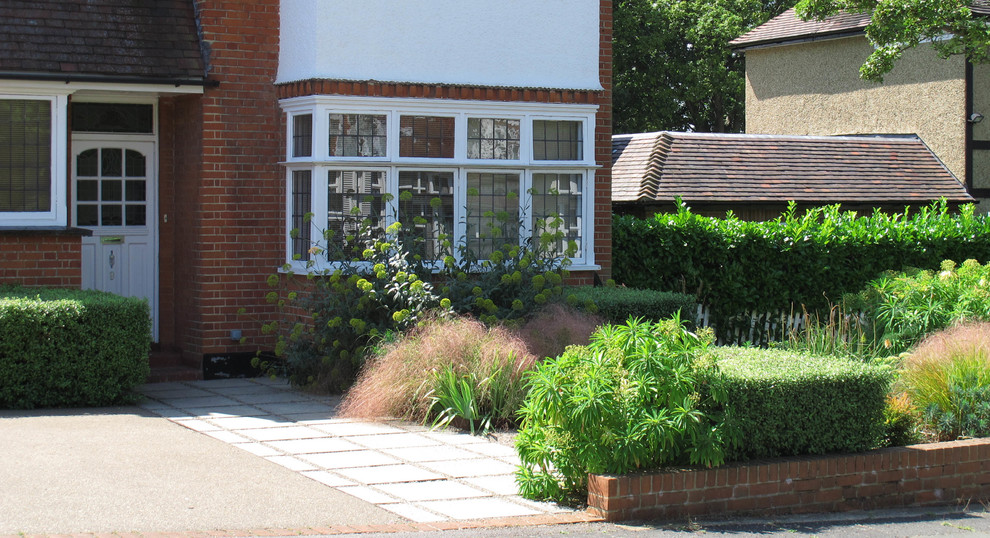 Exempel på en liten modern trädgård i full sol framför huset på sommaren, med en trädgårdsgång och marksten i betong