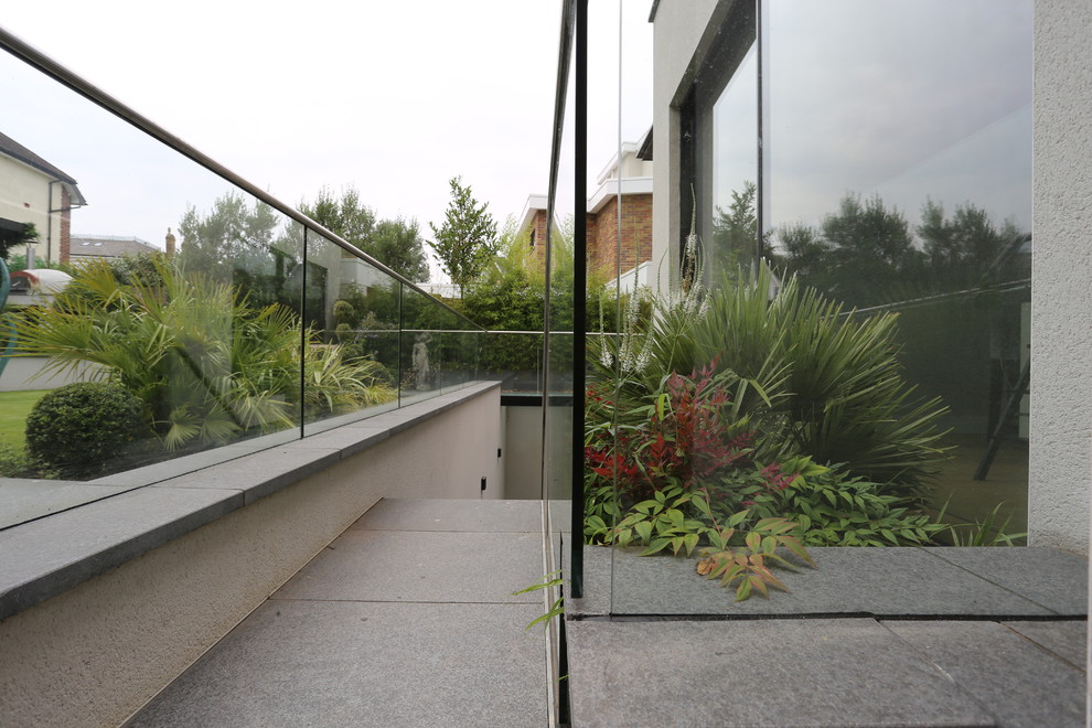 Photo of a medium sized modern back formal full sun garden for summer in London with a water feature and natural stone paving.