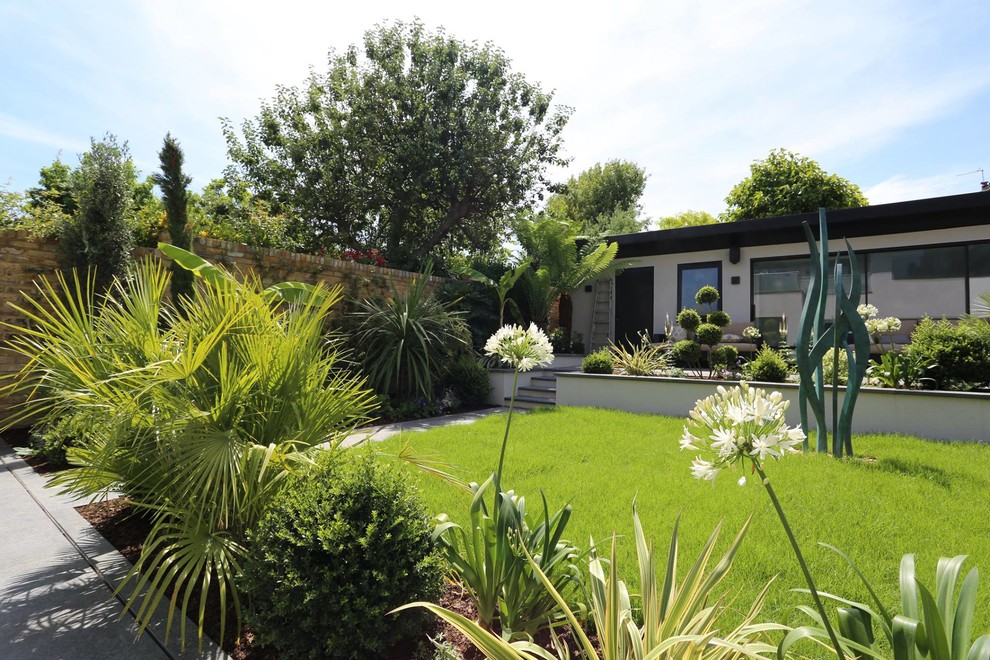 Modelo de jardín minimalista de tamaño medio en verano en patio trasero con jardín francés, fuente, exposición total al sol y adoquines de piedra natural