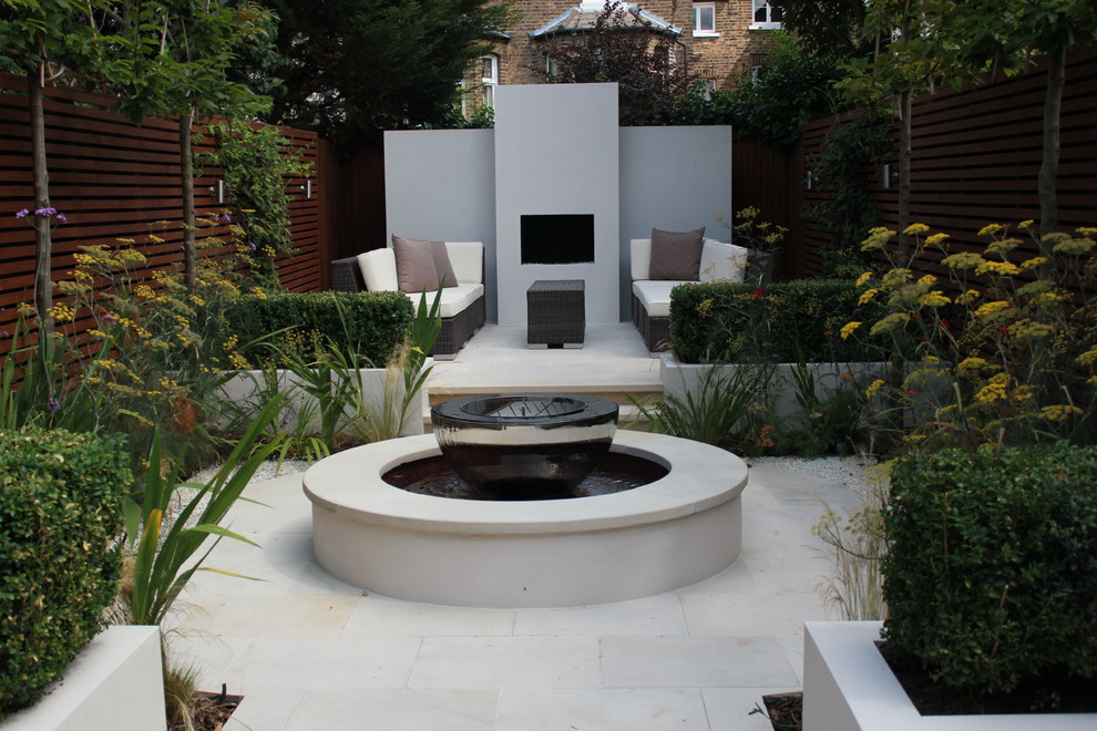 Medium sized contemporary back formal partial sun garden for autumn in London with a water feature and natural stone paving.