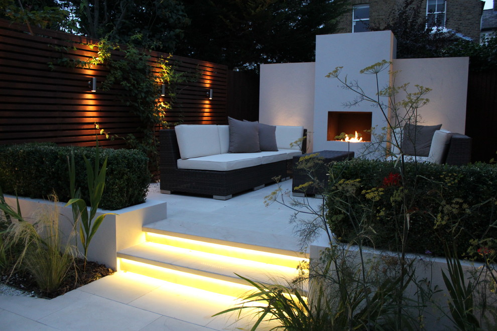 Geometrischer, Mittelgroßer Moderner Garten hinter dem Haus, im Herbst mit Feuerstelle, direkter Sonneneinstrahlung und Natursteinplatten in London
