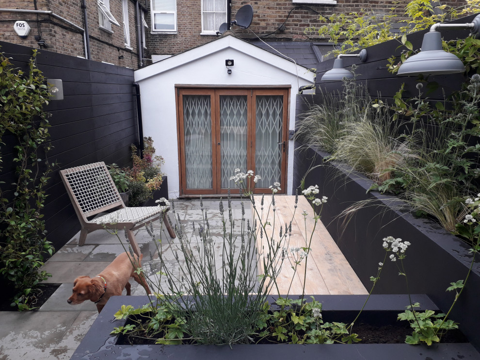 Foto di un piccolo giardino minimal esposto a mezz'ombra dietro casa in primavera con pavimentazioni in pietra naturale e recinzione in legno