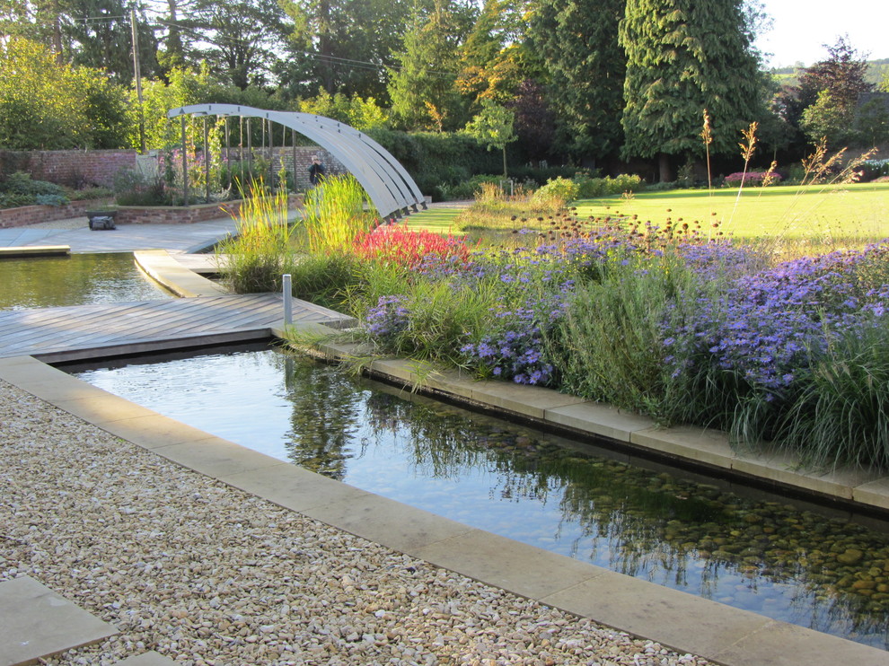 Inspiration for a large contemporary back full sun garden for summer in Gloucestershire with a water feature and natural stone paving.