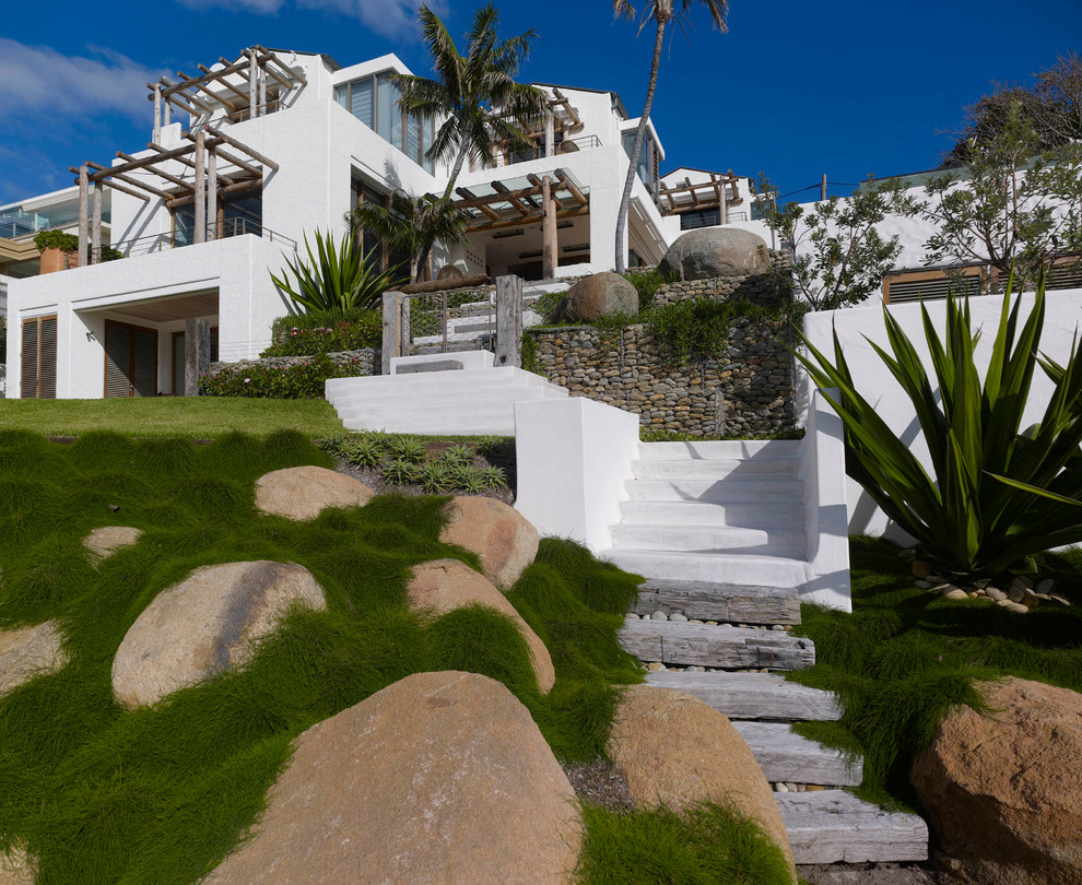 Ispirazione per un grande giardino tropicale dietro casa con scale