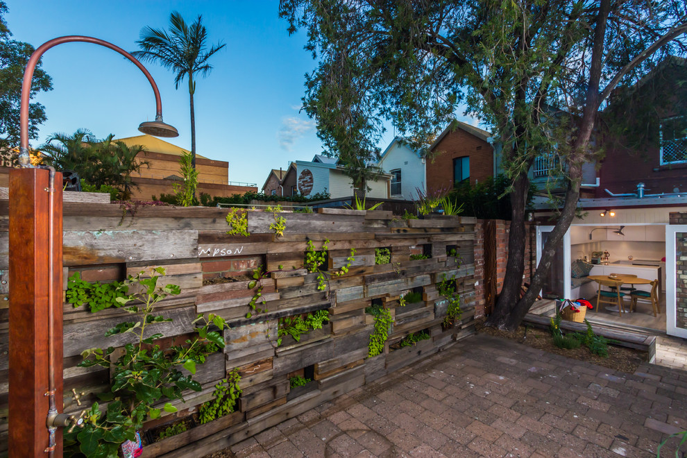 This is an example of a small rustic courtyard xeriscape partial sun garden for spring in Newcastle - Maitland with a living wall and concrete paving.