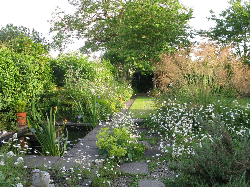 Klassischer Garten hinter dem Haus mit direkter Sonneneinstrahlung, Betonboden und Wasserspiel in West Midlands