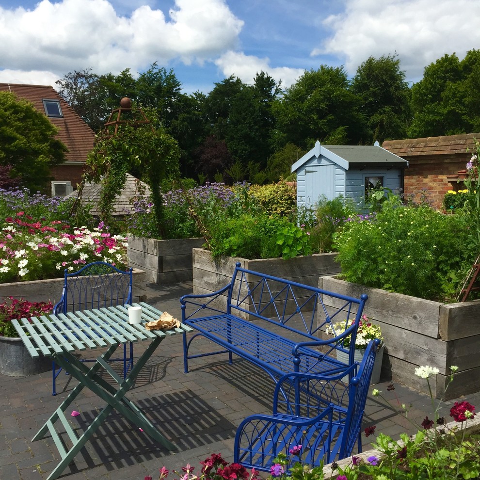 На фото: солнечный участок и сад в стиле кантри с хорошей освещенностью и мощением клинкерной брусчаткой