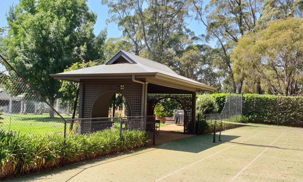 Photo of a large rural back full sun garden in Wollongong with an outdoor sport court and gravel.