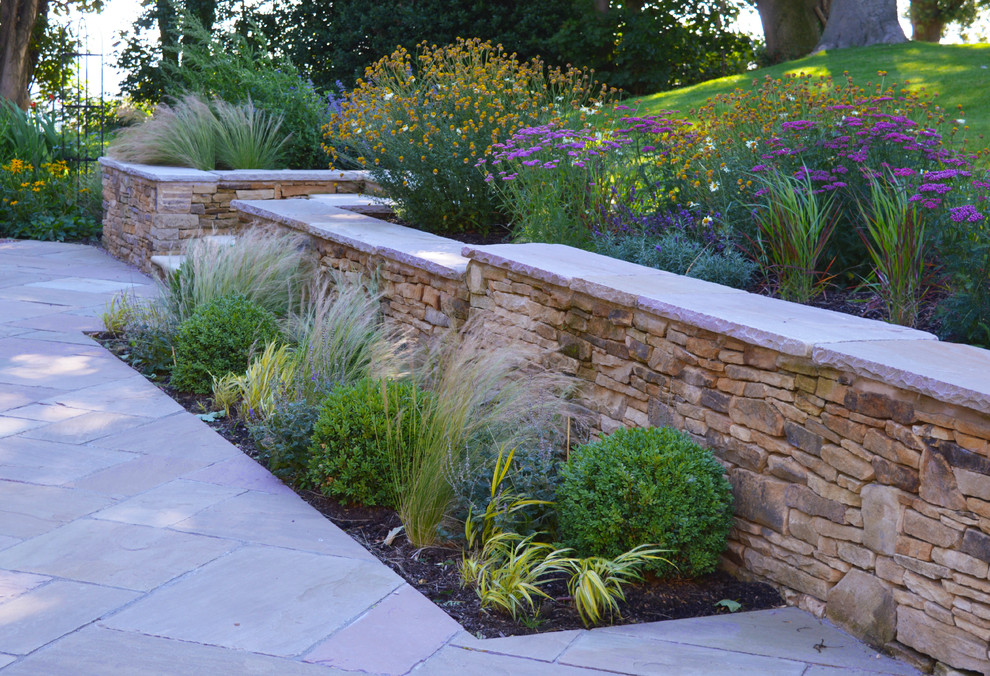 This is an example of a large traditional partial sun front yard stone landscaping in Other for summer.