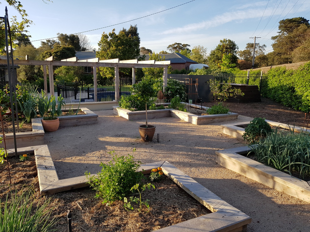 This is an example of a rural back formal full sun garden for summer in Melbourne with a vegetable patch and gravel.