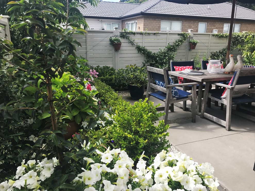 На фото: маленький солнечный, летний регулярный сад на переднем дворе в классическом стиле с садовой дорожкой или калиткой, хорошей освещенностью и мощением тротуарной плиткой для на участке и в саду