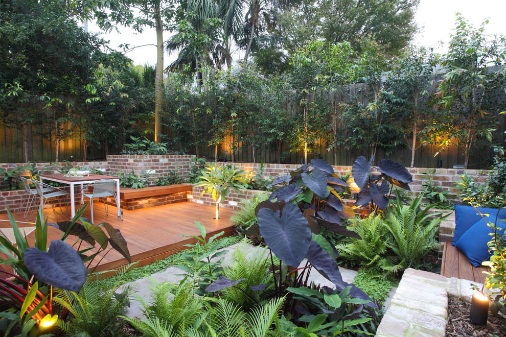 This is an example of a small tropical full sun courtyard landscaping in Sydney with decking for summer.