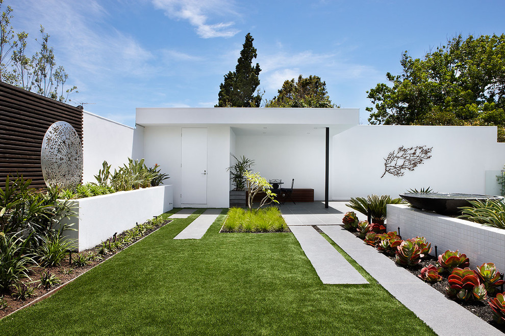 Diseño de jardín actual de tamaño medio en patio trasero con fuente y exposición total al sol