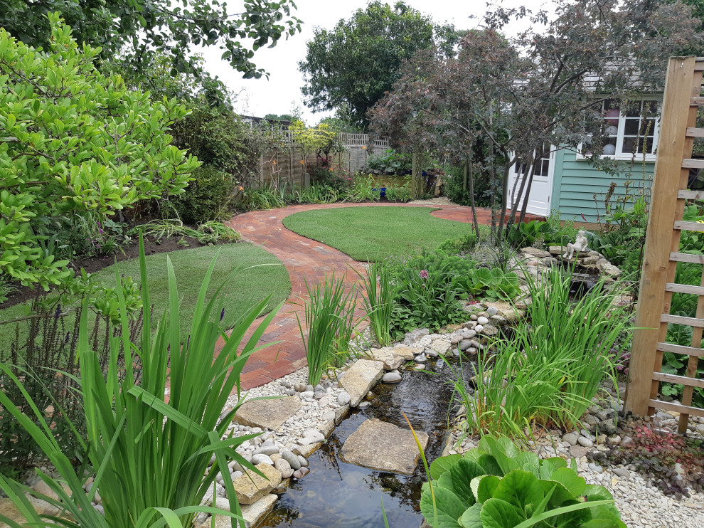 Aménagement d'un jardin arrière campagne de taille moyenne avec un bassin et des galets de rivière.