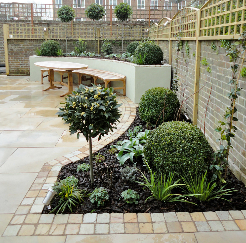 This is an example of a small contemporary back full sun garden in London with natural stone paving.