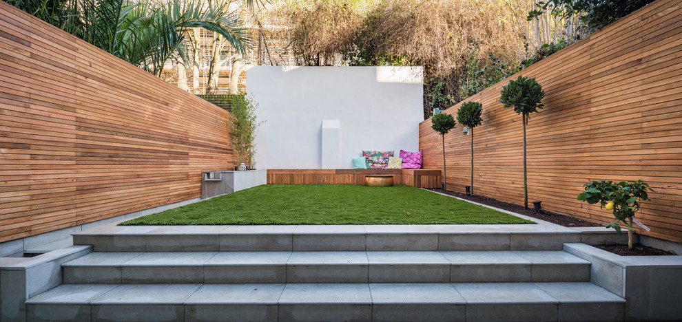 This is an example of a medium sized contemporary back formal partial sun garden for summer in London with a water feature and concrete paving.