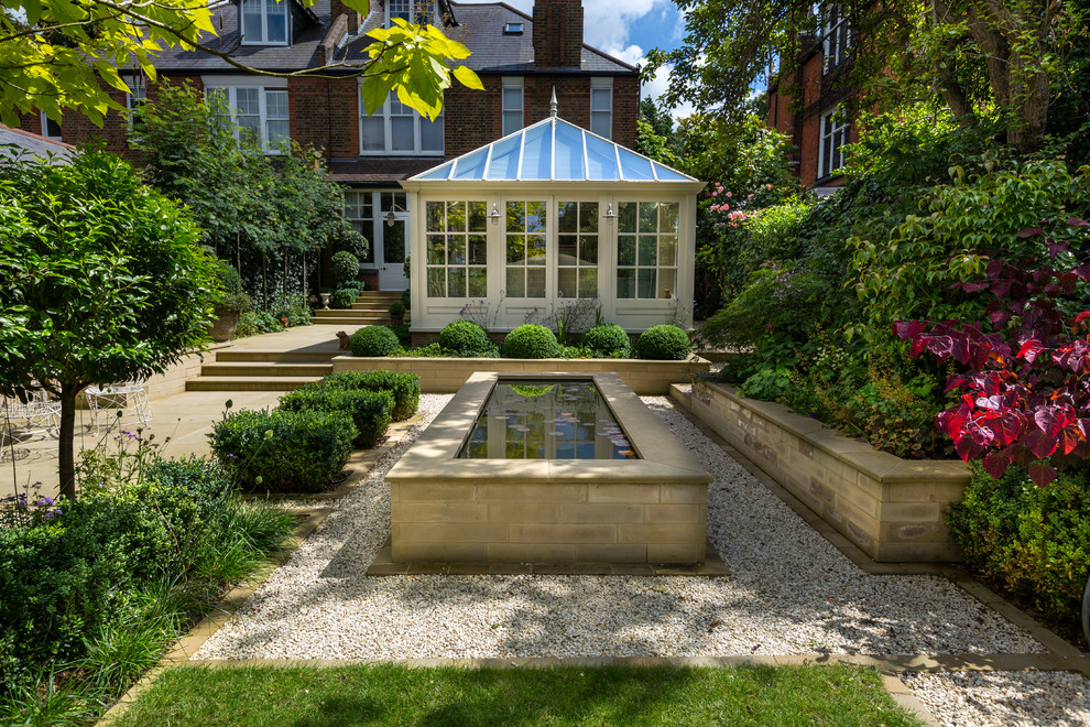 Diseño de jardín clásico de tamaño medio en patio trasero con jardín francés, estanque y gravilla