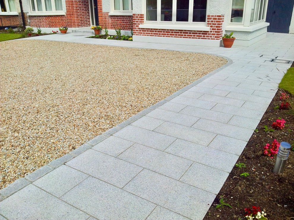 Photo of a large classic front driveway full sun garden for summer in Dublin with a garden path, natural stone paving and a stone fence.