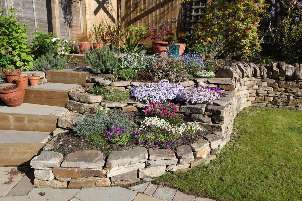 Idée de décoration pour un jardin arrière tradition de taille moyenne avec un mur de soutènement et des pavés en pierre naturelle.