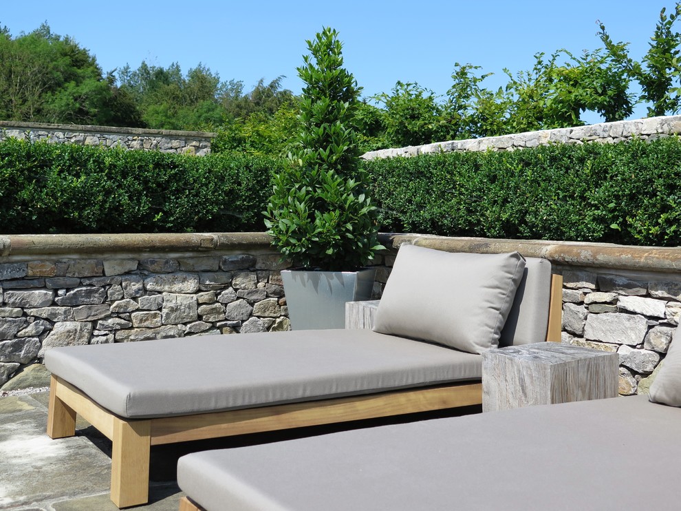 Idee per un ampio giardino formale classico esposto in pieno sole dietro casa in estate con un muro di contenimento e pavimentazioni in pietra naturale
