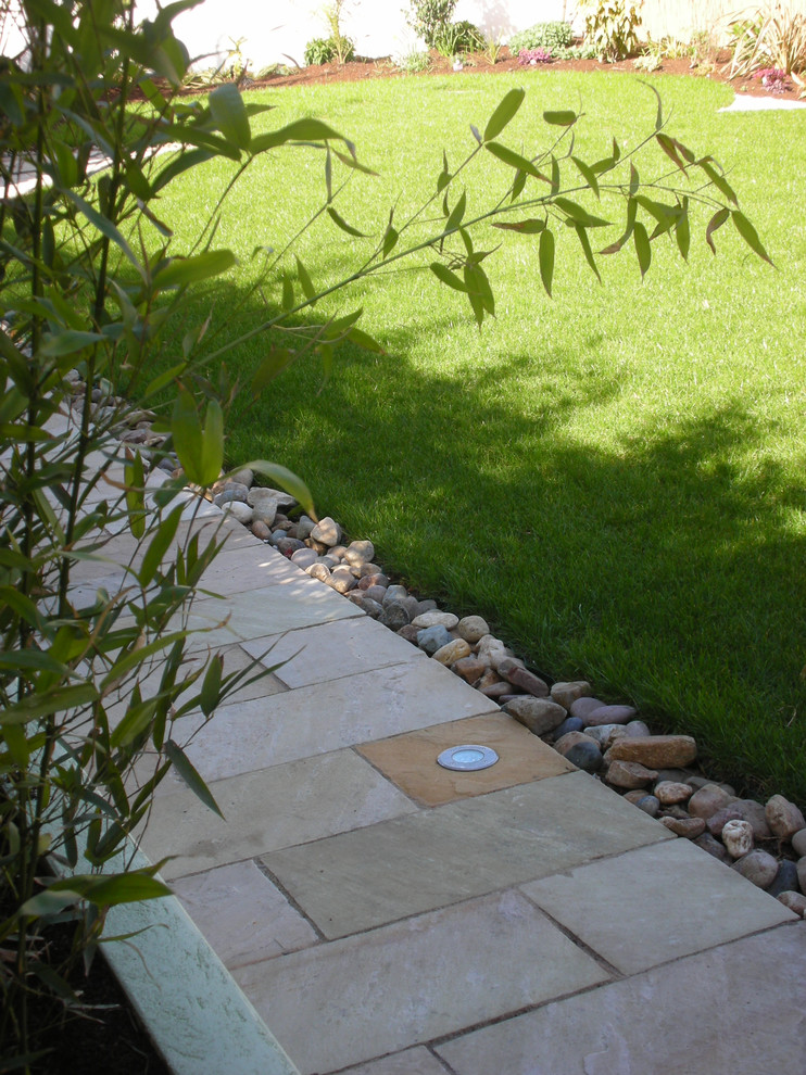 Immagine di un grande giardino formale design esposto a mezz'ombra dietro casa in primavera con un ingresso o sentiero, pavimentazioni in pietra naturale e recinzione in legno