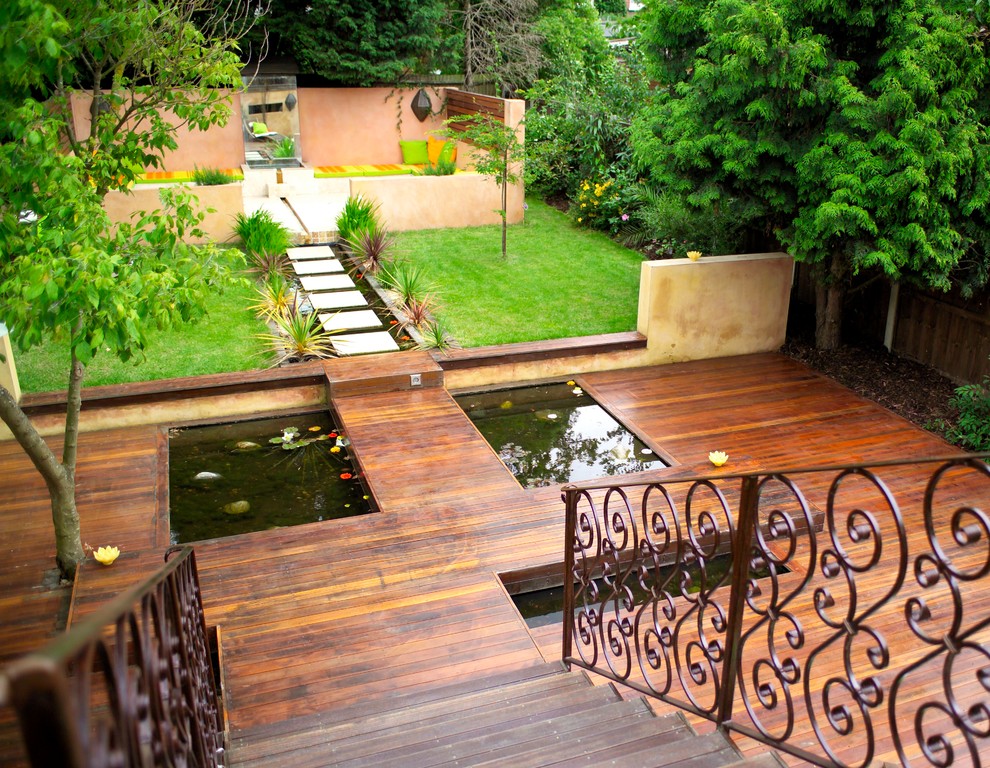 Photo of a large contemporary full sun backyard water fountain landscape in London with decking.