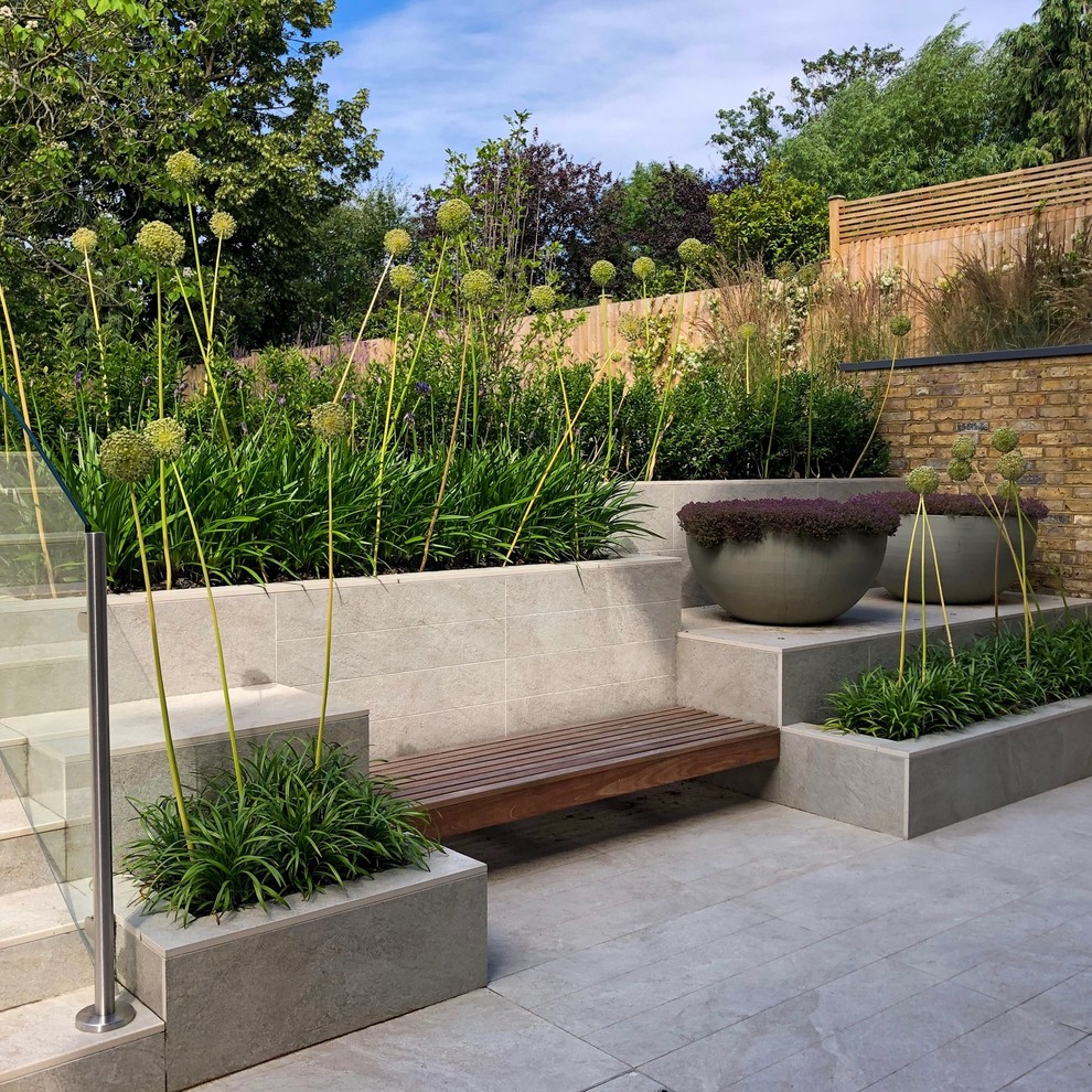 Ispirazione per un giardino formale minimal esposto a mezz'ombra di medie dimensioni e dietro casa in estate con un muro di contenimento e pavimentazioni in pietra naturale