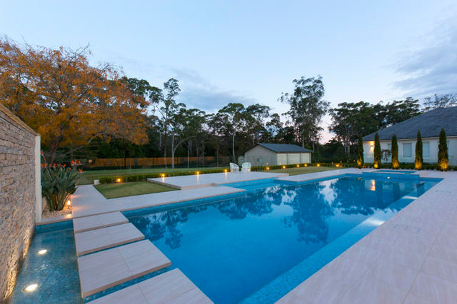 Cette image montre une très grande piscine arrière minimaliste avec des pavés en pierre naturelle.