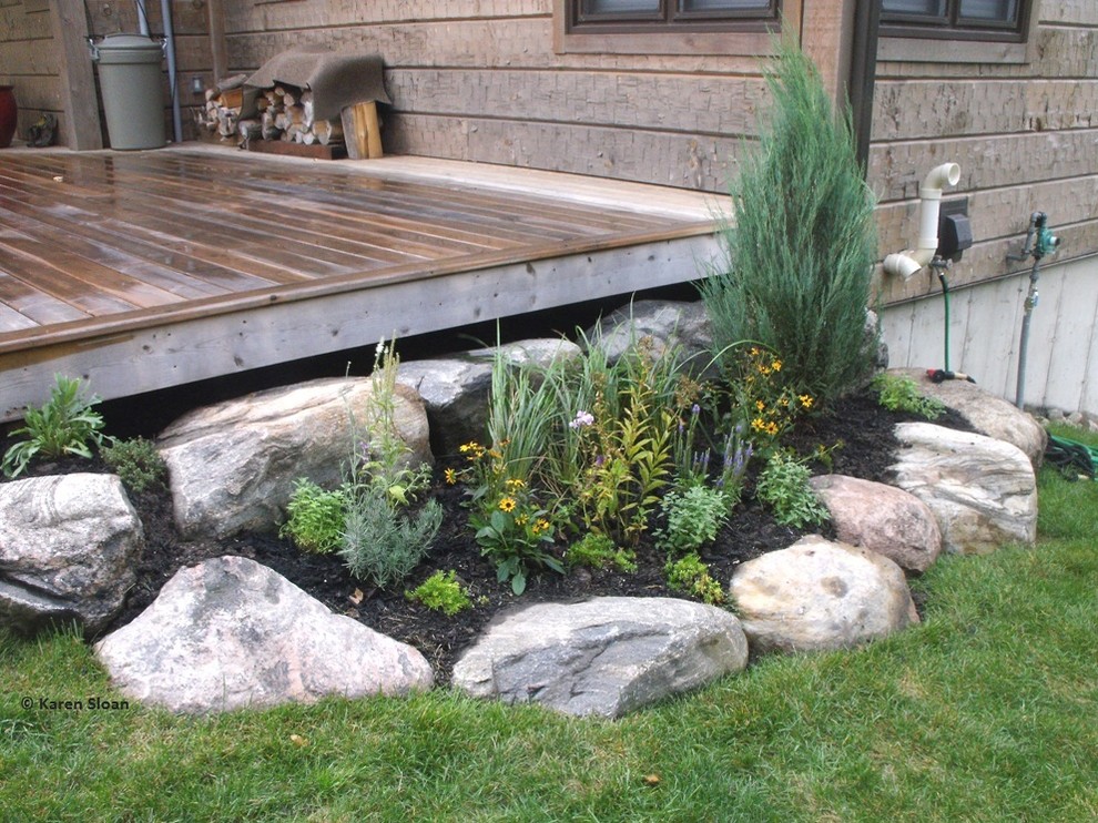This is an example of a large traditional front driveway full sun garden in Toronto with a retaining wall and decking.
