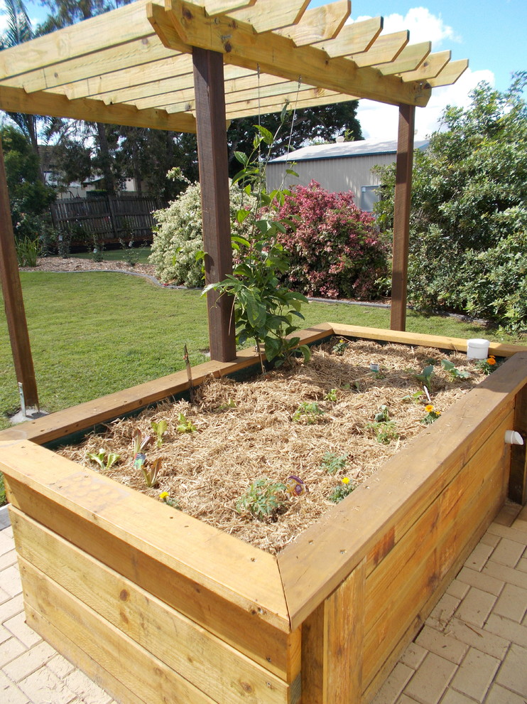 Imagen de jardín de secano tradicional de tamaño medio en verano en patio trasero con huerto, exposición total al sol y adoquines de hormigón