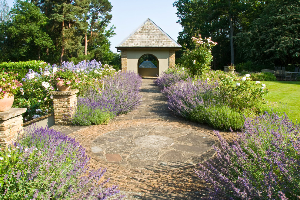 Foto di un grande giardino formale tradizionale esposto in pieno sole dietro casa in estate con pavimentazioni in pietra naturale