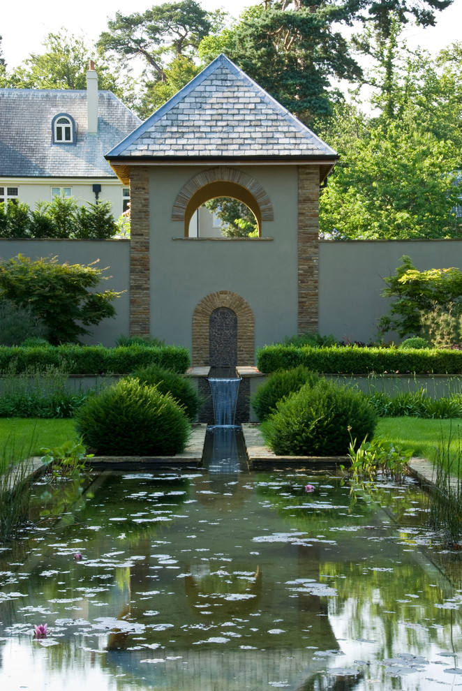 Immagine di un grande giardino formale american style esposto a mezz'ombra dietro casa in estate con fontane