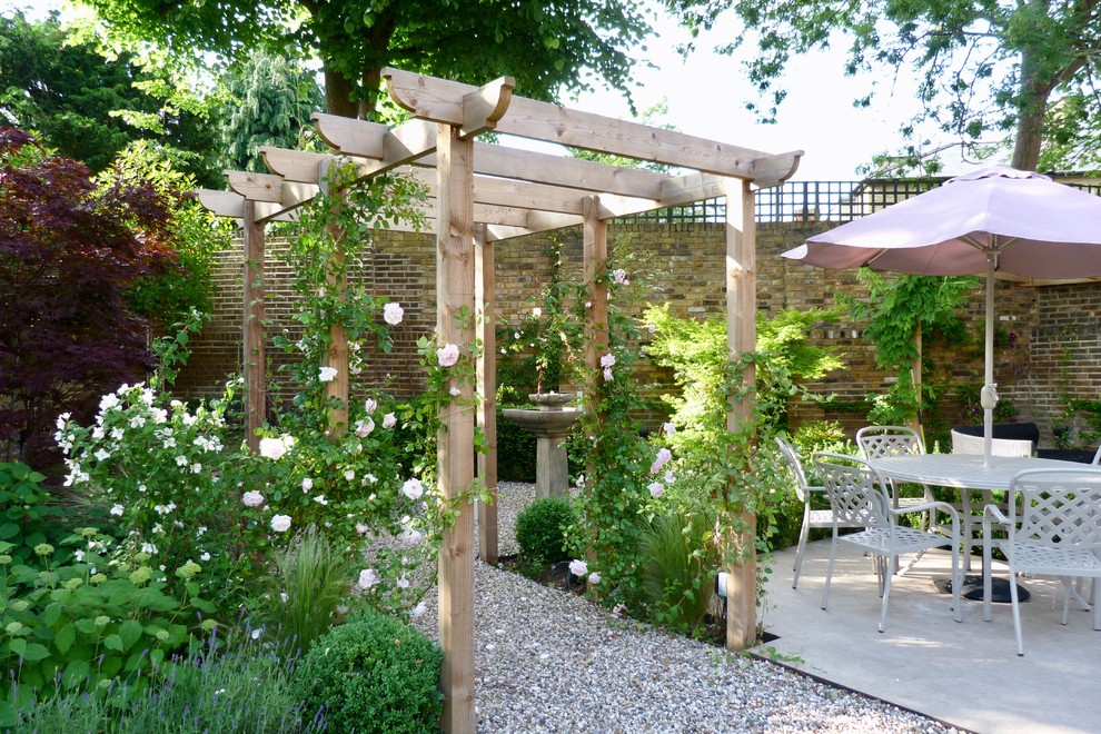 На фото: участок и сад в классическом стиле с полуденной тенью, покрытием из гравия и с перголой